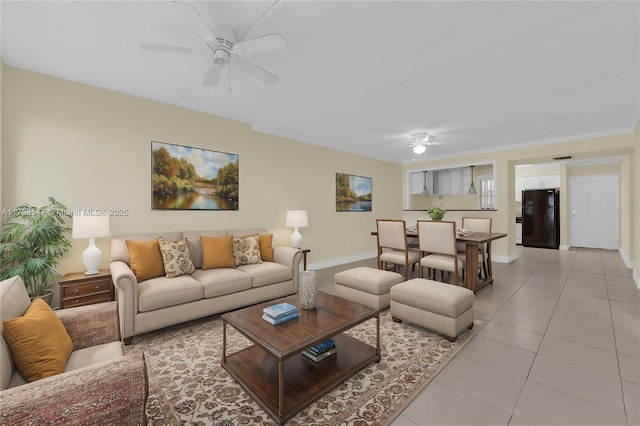 living room with light tile patterned floors, a ceiling fan, and baseboards