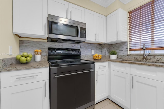 kitchen featuring black / electric stove, a sink, white cabinets, decorative backsplash, and stainless steel microwave