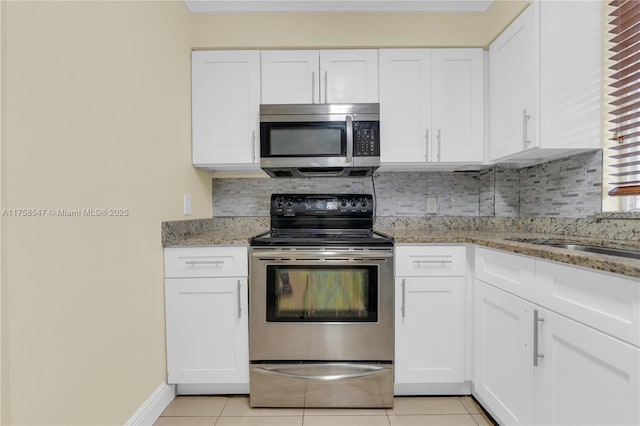 kitchen featuring stainless steel appliances, light tile patterned flooring, backsplash, and white cabinetry