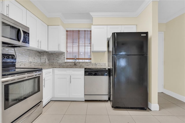 kitchen featuring light stone counters, appliances with stainless steel finishes, white cabinets, and a sink