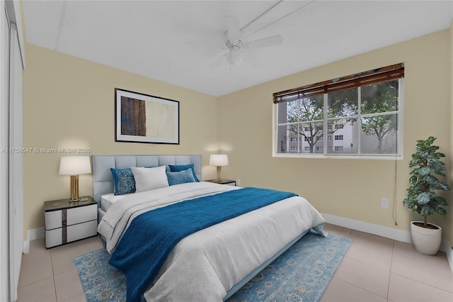 tiled bedroom with ceiling fan and baseboards