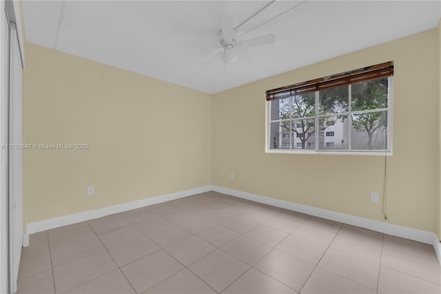 empty room featuring ceiling fan, baseboards, and light tile patterned floors