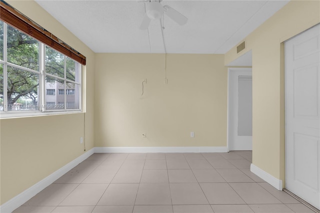 empty room with light tile patterned floors, baseboards, visible vents, and a ceiling fan