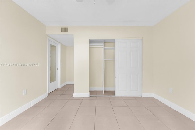 unfurnished bedroom with a closet, light tile patterned flooring, visible vents, and baseboards