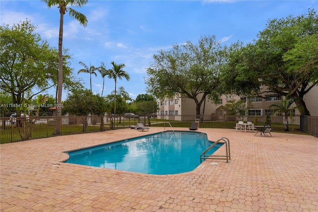 pool with a patio area and fence