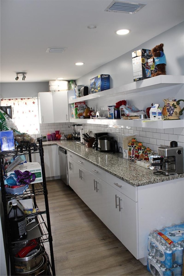 kitchen featuring visible vents, light wood-style floors, stainless steel dishwasher, decorative backsplash, and open shelves
