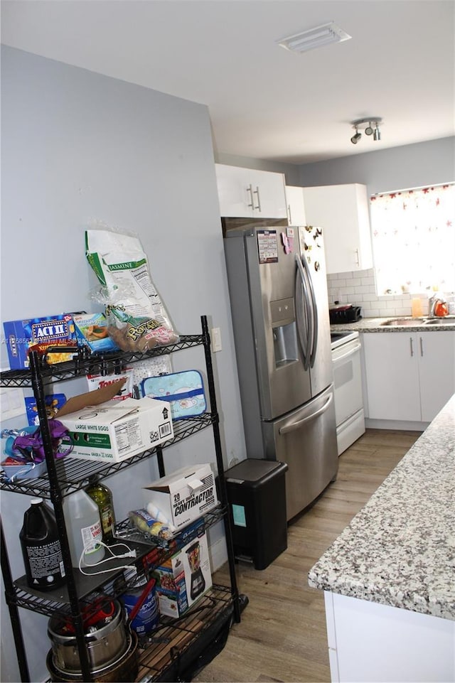 kitchen featuring electric range, a sink, white cabinetry, light wood-type flooring, and stainless steel refrigerator with ice dispenser