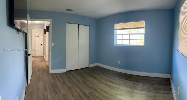 unfurnished bedroom with baseboards, a closet, visible vents, and wood finished floors