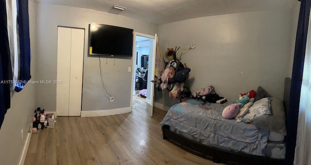 bedroom with wood finished floors, visible vents, and baseboards