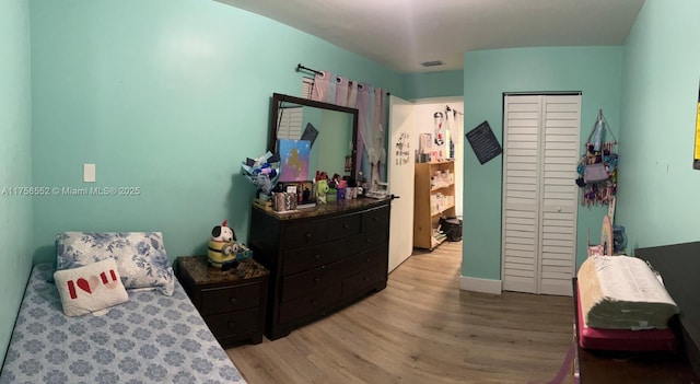 bedroom with light wood-style floors, a closet, and visible vents
