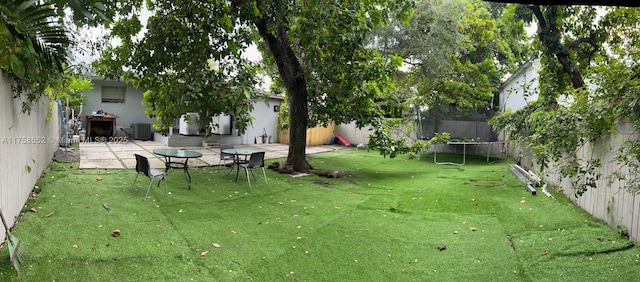 view of yard featuring central AC, a patio, a trampoline, and a fenced backyard
