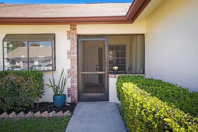 doorway to property featuring stone siding, roof with shingles, and stucco siding