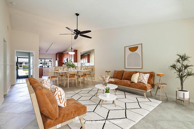 living area with lofted ceiling, ceiling fan, light tile patterned floors, and baseboards