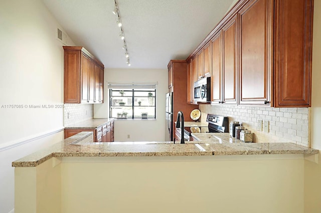 kitchen with light stone countertops, appliances with stainless steel finishes, and brown cabinetry