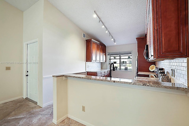 kitchen with baseboards, stainless steel microwave, light stone countertops, a textured ceiling, and backsplash