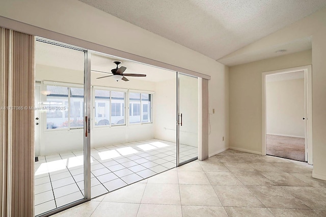 unfurnished room featuring light tile patterned floors, ceiling fan, a textured ceiling, baseboards, and vaulted ceiling