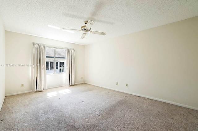 carpeted empty room with ceiling fan, a textured ceiling, and baseboards