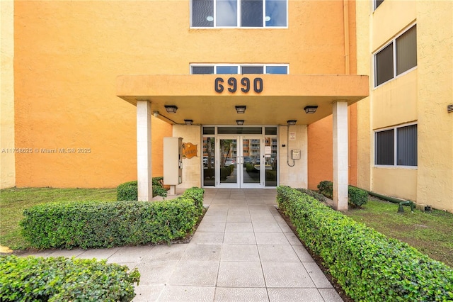 entrance to property featuring french doors and stucco siding