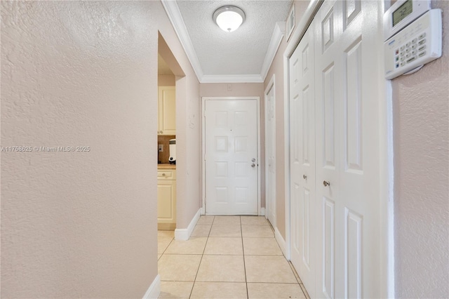 hall with baseboards, ornamental molding, a textured ceiling, and light tile patterned flooring