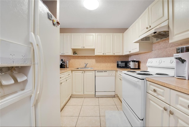 kitchen with white appliances, light tile patterned floors, light countertops, under cabinet range hood, and a sink