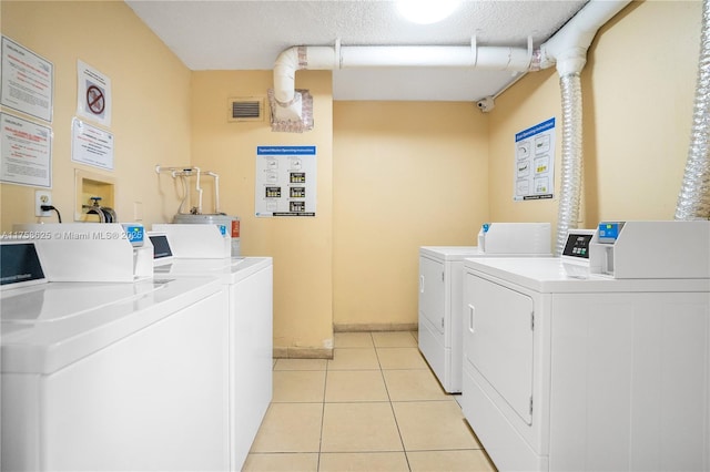 shared laundry area featuring light tile patterned floors, a textured ceiling, visible vents, baseboards, and independent washer and dryer