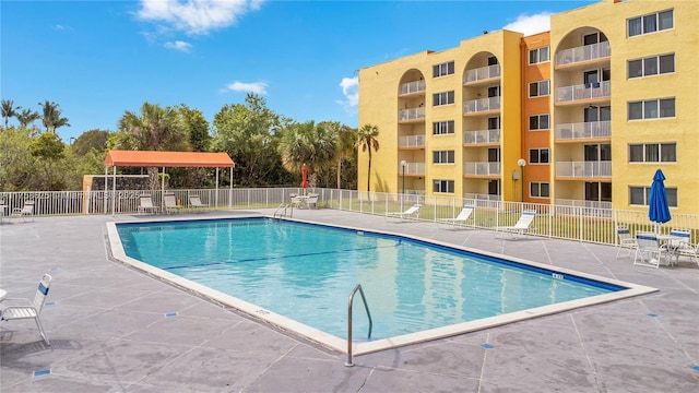 community pool with fence and a patio