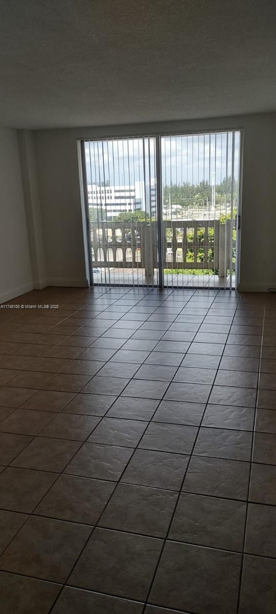 spare room with tile patterned flooring, baseboards, and a textured ceiling