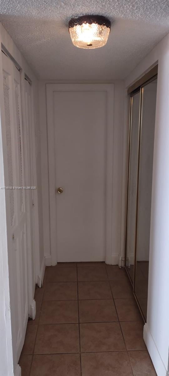 corridor featuring light tile patterned floors and a textured ceiling