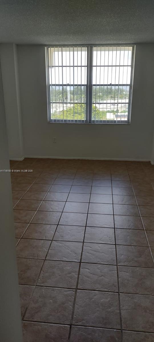 tiled empty room featuring a textured ceiling