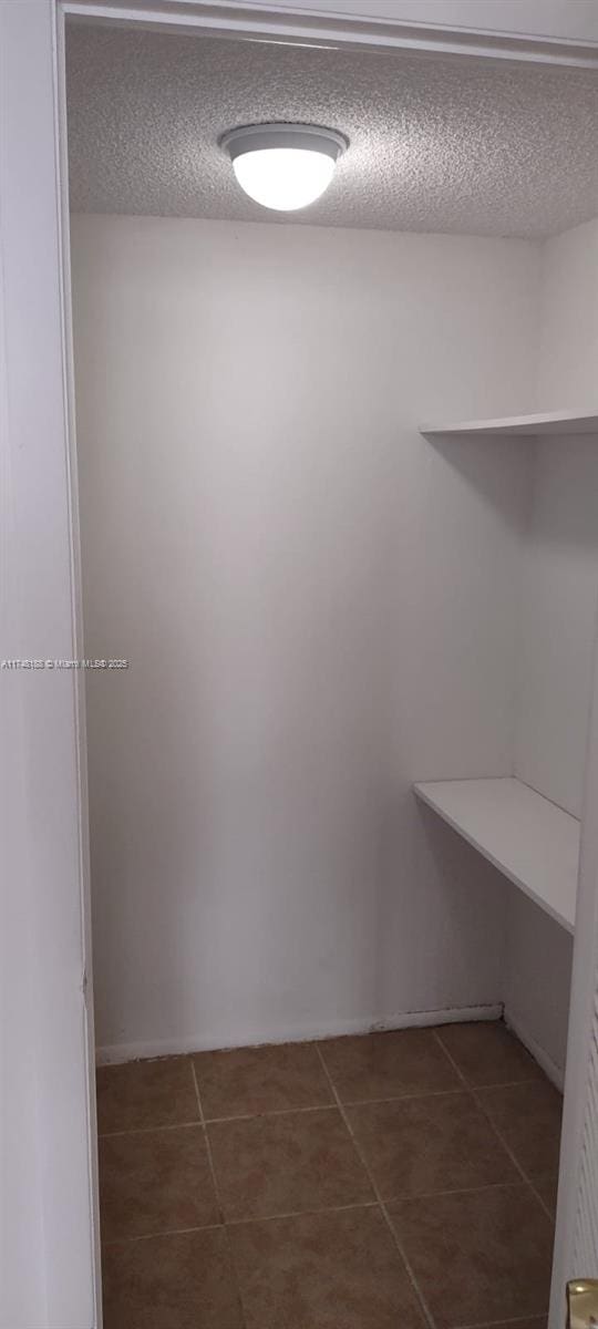 spacious closet featuring dark tile patterned flooring