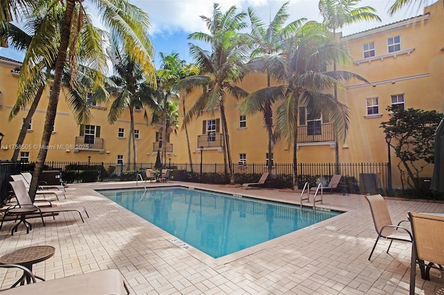 community pool with a patio area and fence