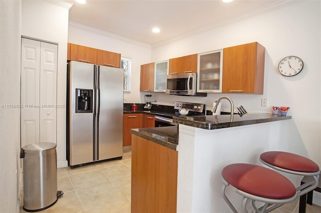 kitchen featuring brown cabinets, crown molding, stainless steel appliances, glass insert cabinets, and a peninsula