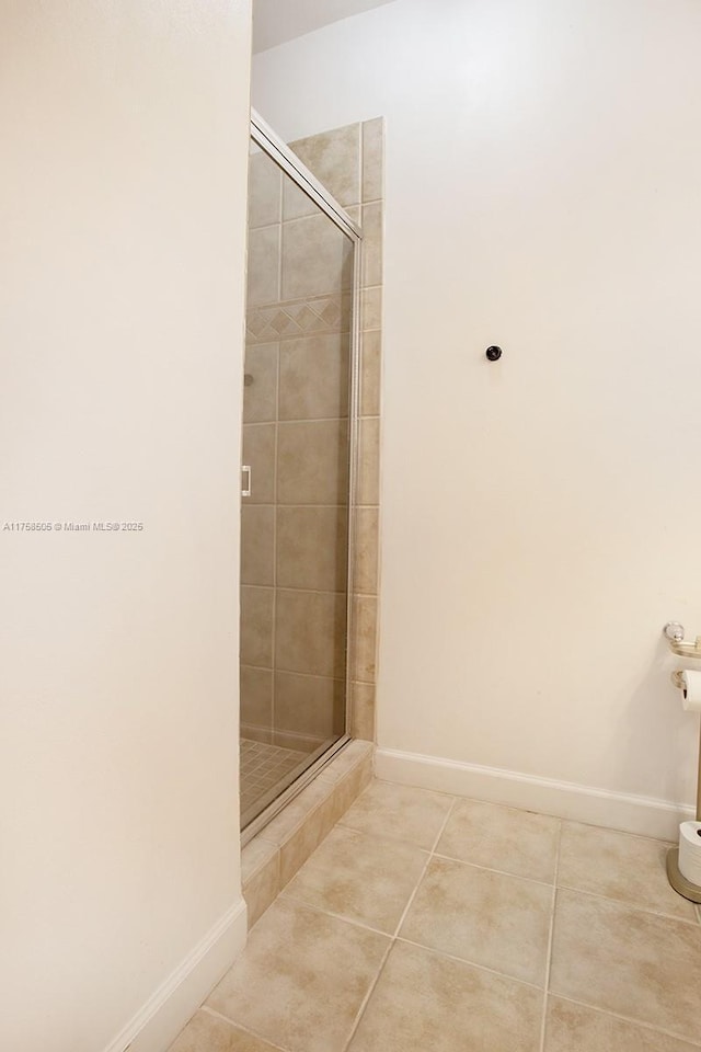 bathroom featuring baseboards, a stall shower, and tile patterned floors