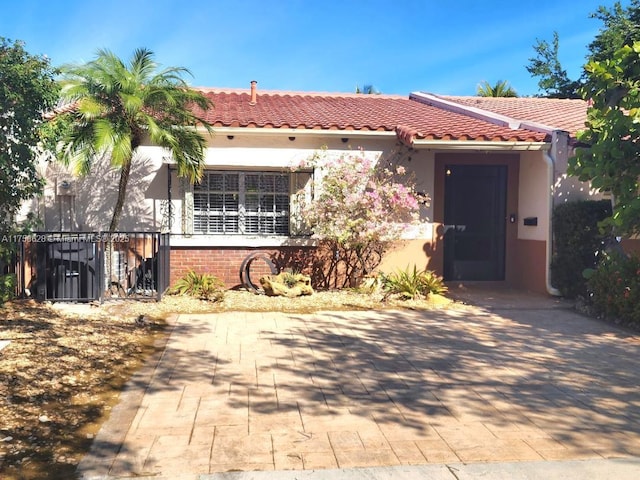 mediterranean / spanish house featuring a tile roof, fence, and stucco siding