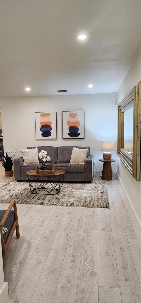 living area featuring visible vents, baseboards, light wood-style flooring, and recessed lighting