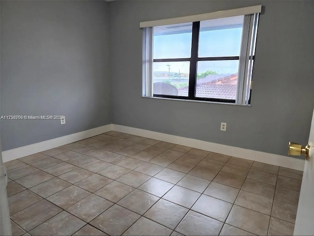 tiled empty room featuring baseboards