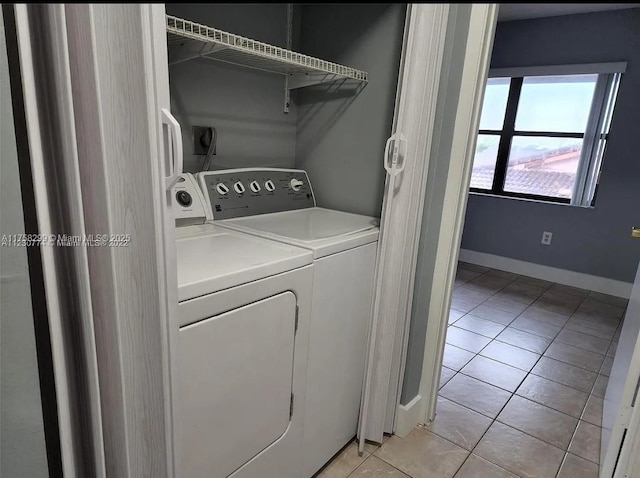 clothes washing area with laundry area, baseboards, washer and clothes dryer, and light tile patterned flooring