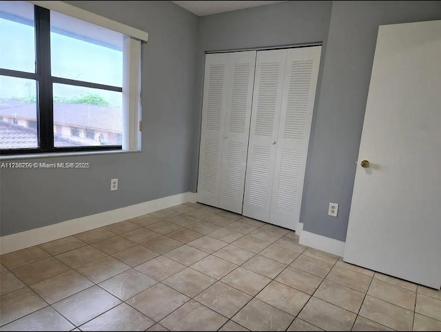 unfurnished bedroom featuring light tile patterned floors, a closet, and baseboards