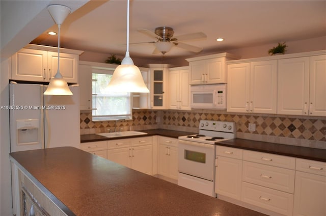 kitchen with white appliances, tasteful backsplash, dark countertops, white cabinetry, and a sink