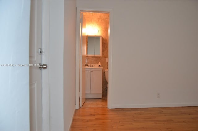 corridor featuring baseboards and light wood finished floors