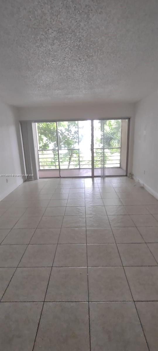 unfurnished room featuring a textured ceiling, baseboards, and light tile patterned floors