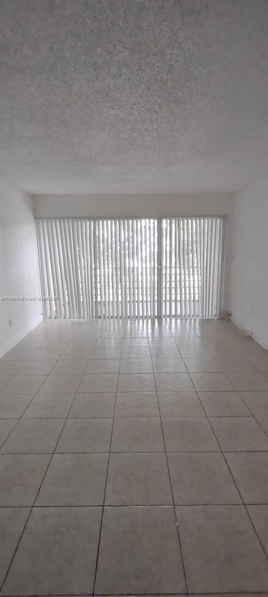 tiled spare room featuring a textured ceiling