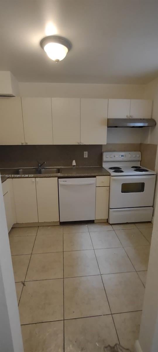 kitchen featuring white appliances, light tile patterned floors, and white cabinets