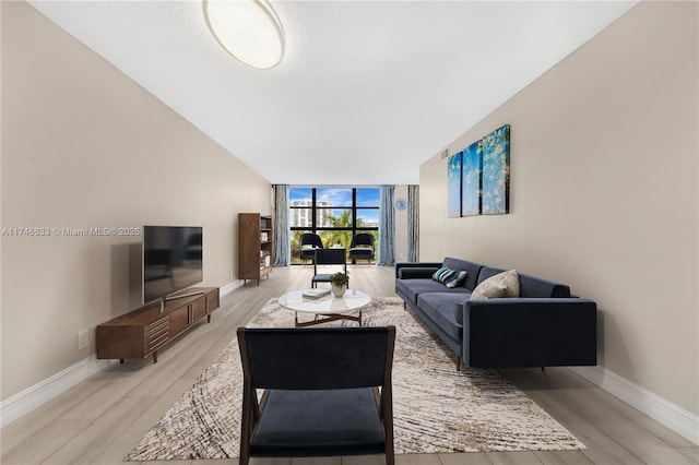 living room with expansive windows, light wood-style flooring, and baseboards