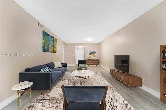 living room featuring visible vents, light wood-style flooring, and baseboards