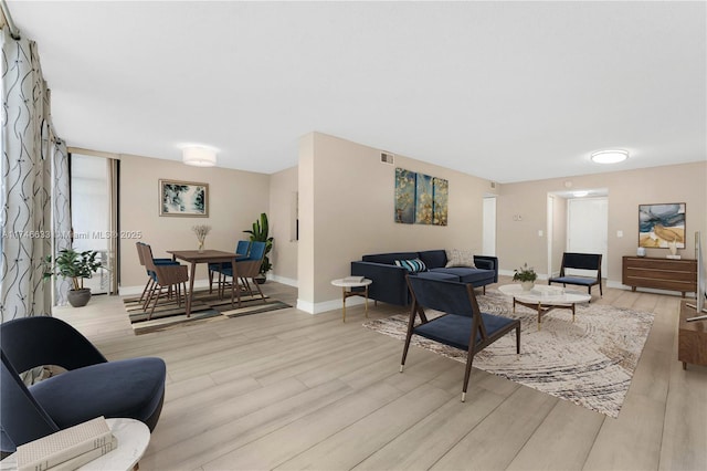 living room with light wood-type flooring, baseboards, and visible vents