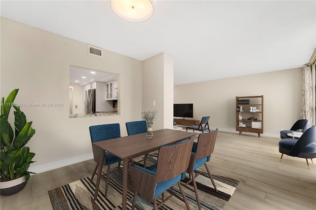 dining area with light wood finished floors, baseboards, and visible vents