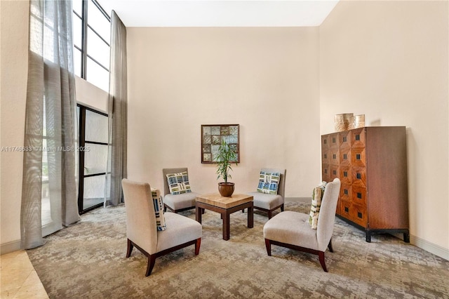 living area featuring a towering ceiling and baseboards