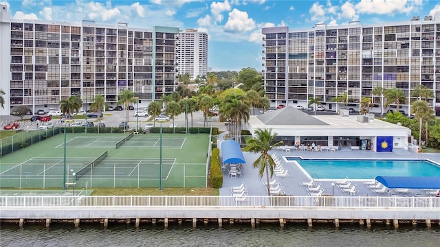 exterior space with a tennis court, a water view, and fence