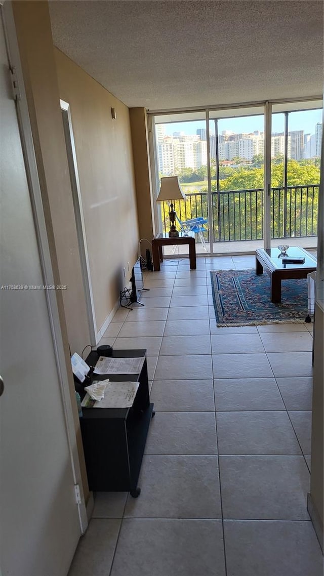 interior space with baseboards, tile patterned floors, a city view, a textured ceiling, and floor to ceiling windows